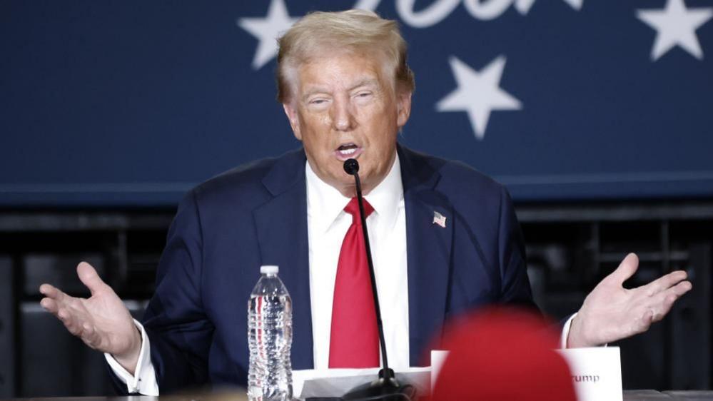 Donald Trump speaking into a microphone at a campaign event