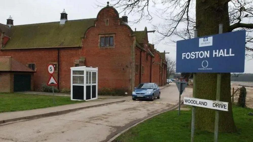 Outside view of HMP Foston Hall with a sign at the entrance