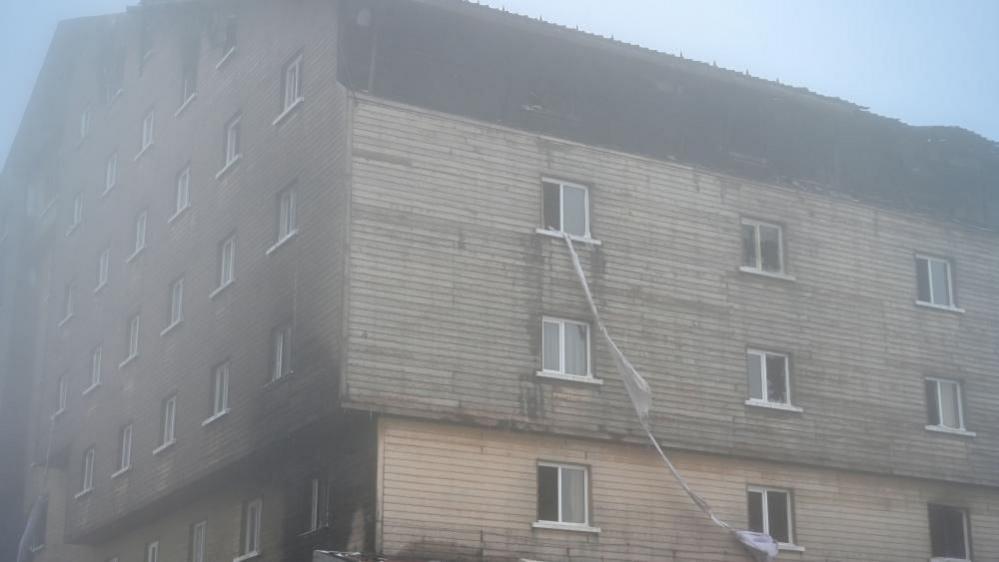 Bedsheets dangle from an upper floor of the Turkish hotel where dozens of guests died in a fire