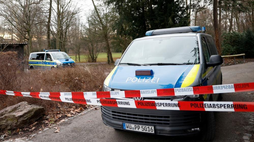 Police vans parked in the park on Wednesday, next to red and white cordon tape