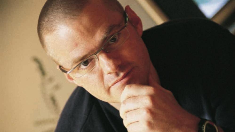 Celebrity chef Heston Blumenthal stares into the camera with his hand on his chin.
