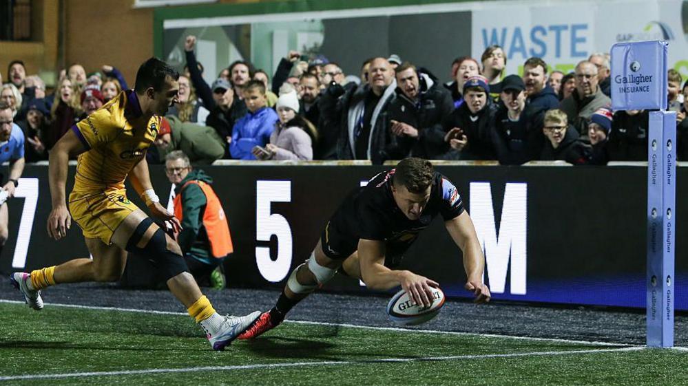 Stefan Coetzee touches down to score a try in the corner for Newcastle Red Bulls as a Northampton player watches on