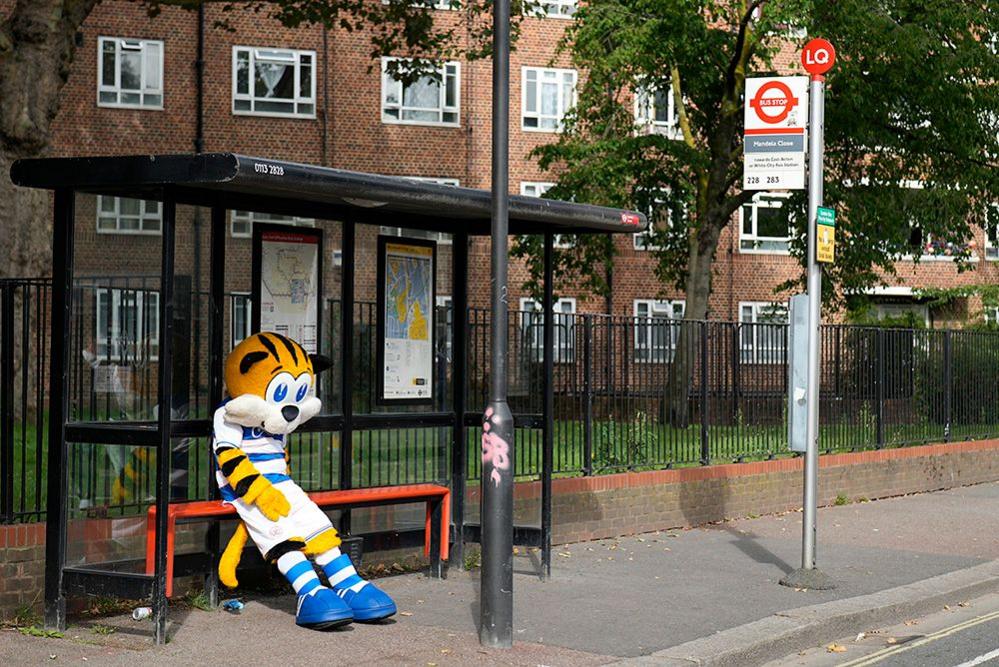 A person dressed as a tiger at a bus stop