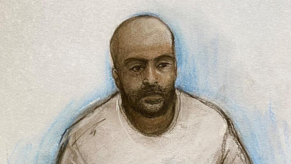 Court artist drawing by Elizabeth Cook of Sudanese national Hadi Alodid, 30 appearing via videolink at Belfast Magistrates Court. He is depicted as having brown skin, no hair with a dark beard. He is drawn as wearing a white top and the background is plain.