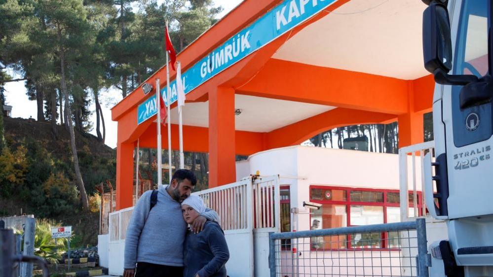 A father and daughter wait at the newly opened Yayladagi border gate to return to Syria