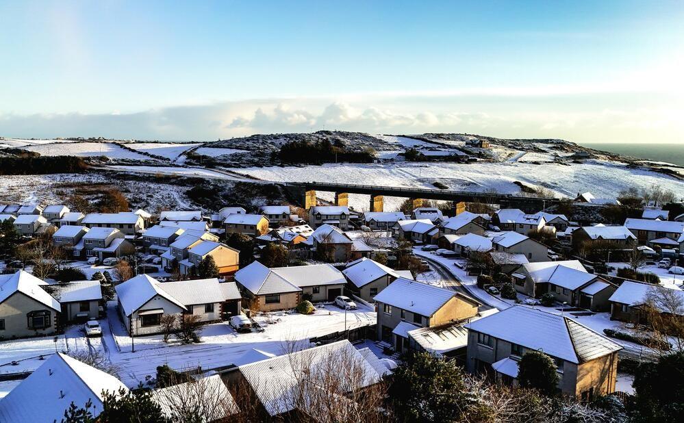 Snowy rooftops from above with snowy hills in the background.