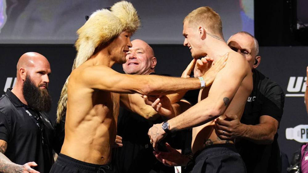 Ian Machado Garry and Shavkat Rakhmonov are separated by security at a UFC weigh-in