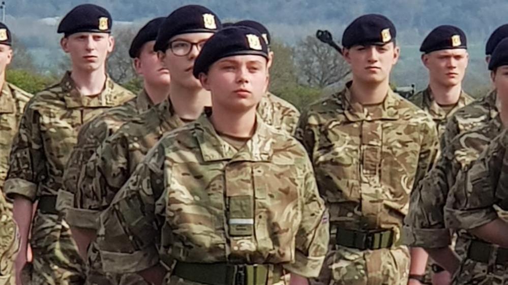 Gunner Beck stands in a group of uniformed soldiers