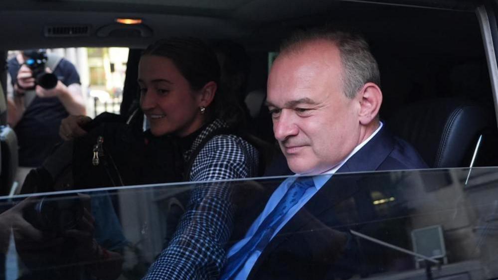 Sir Ed Davey sitting in a car with the window screen half-wound down