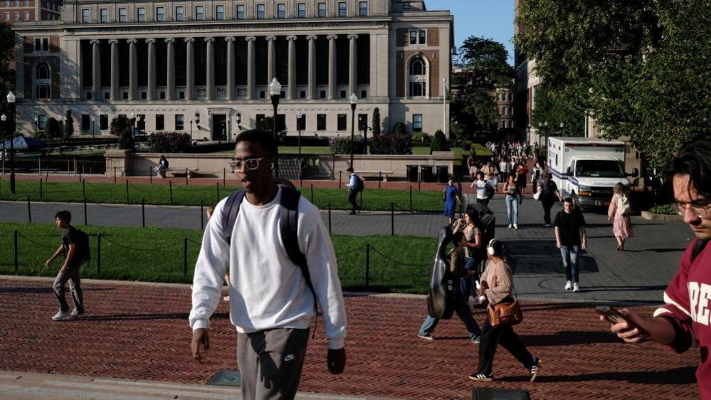 Students walk through Columbia University's campus appearing unbothered by the protest occurring outside the school's gates. 