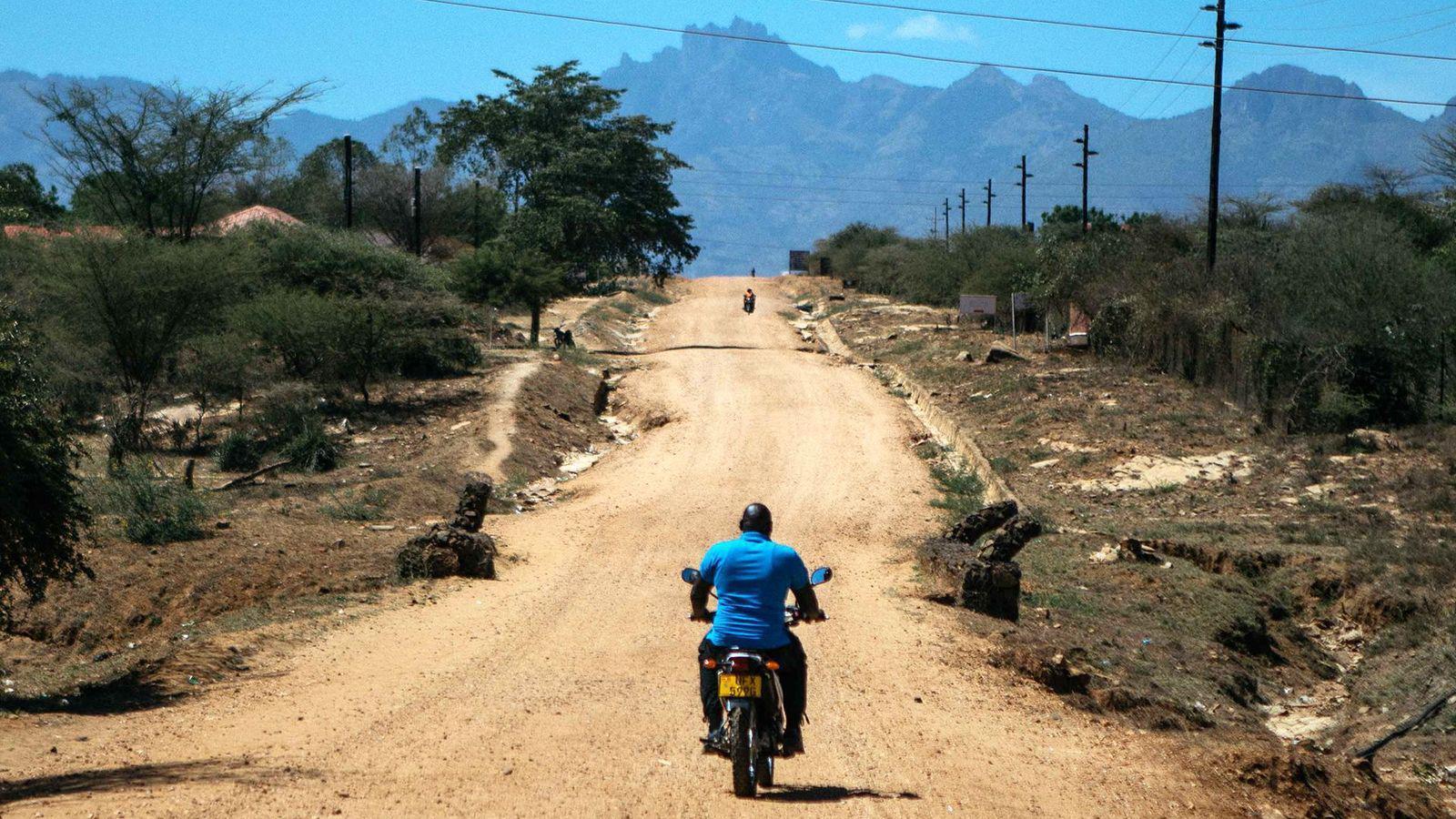 Andrew Ochieng recorriendo un camino en su moto. 
