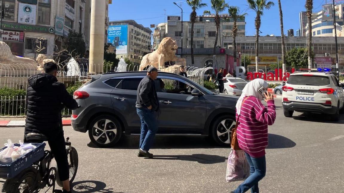 منظر لساحة المنارة في قلب رام الله، ويظهر الناس والسيارات في شوارع المدينة المُزدحمة.