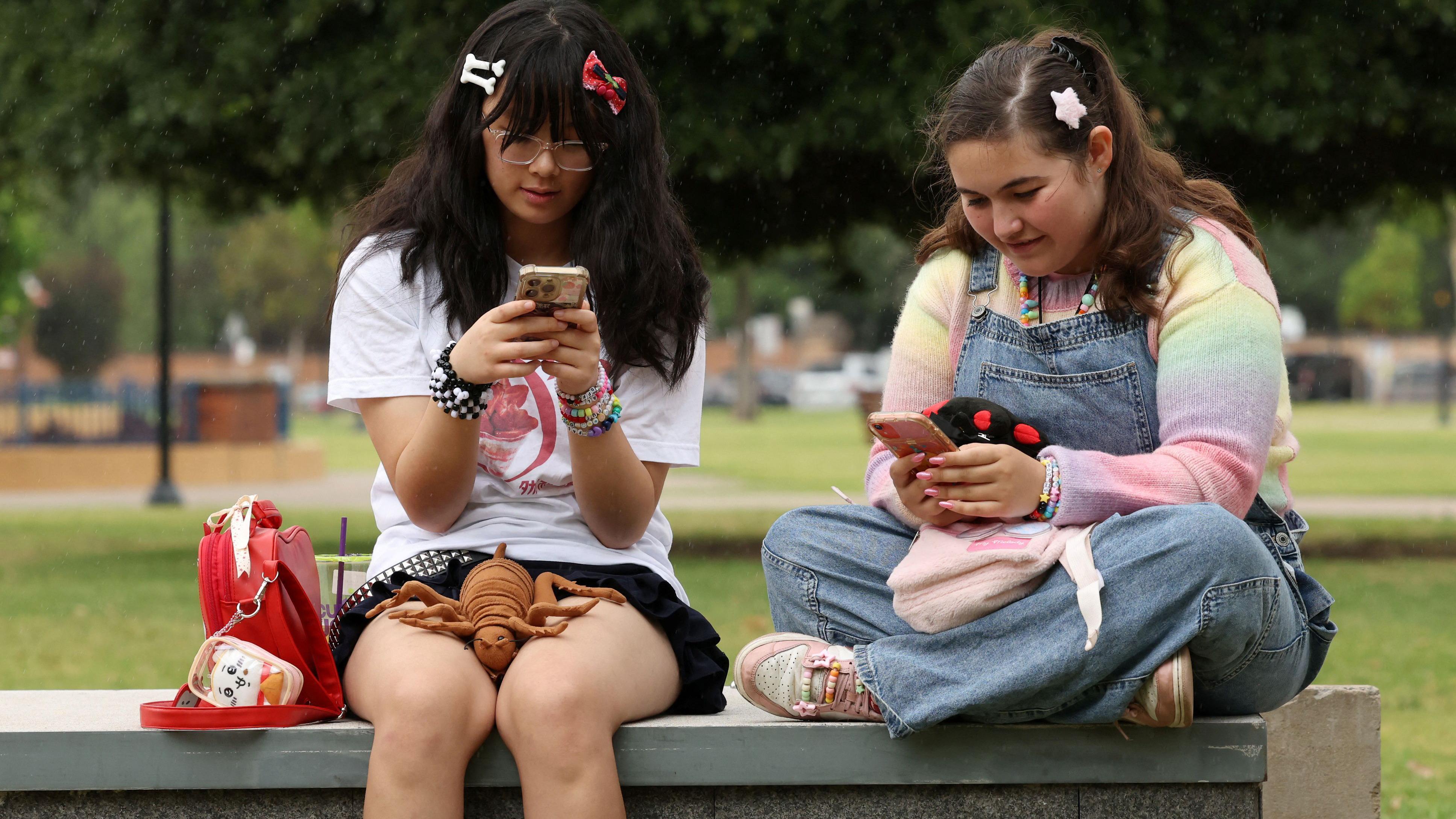 Prvi put u svetu: Australija zabranila društvene mreže za mlađe od 16 godina 1 dve devojčice sede na betonskom bloku i gledaju u telefon