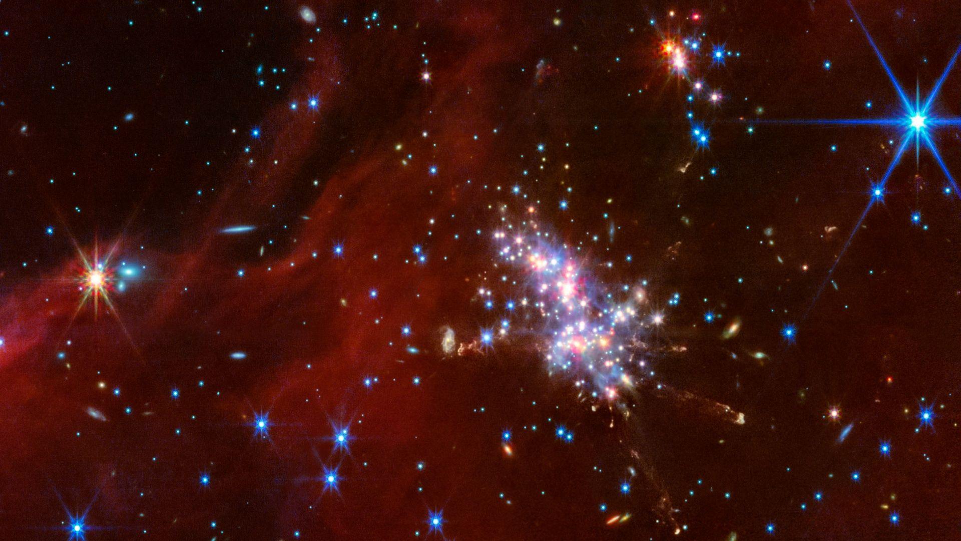 Šarene zvezde, u centru je skup jarko plavih, crvenih i žutih zvezda, sa manjim skupom  iznad dok je bledi crvenkasti oblak iscrtan preko leve strane slike