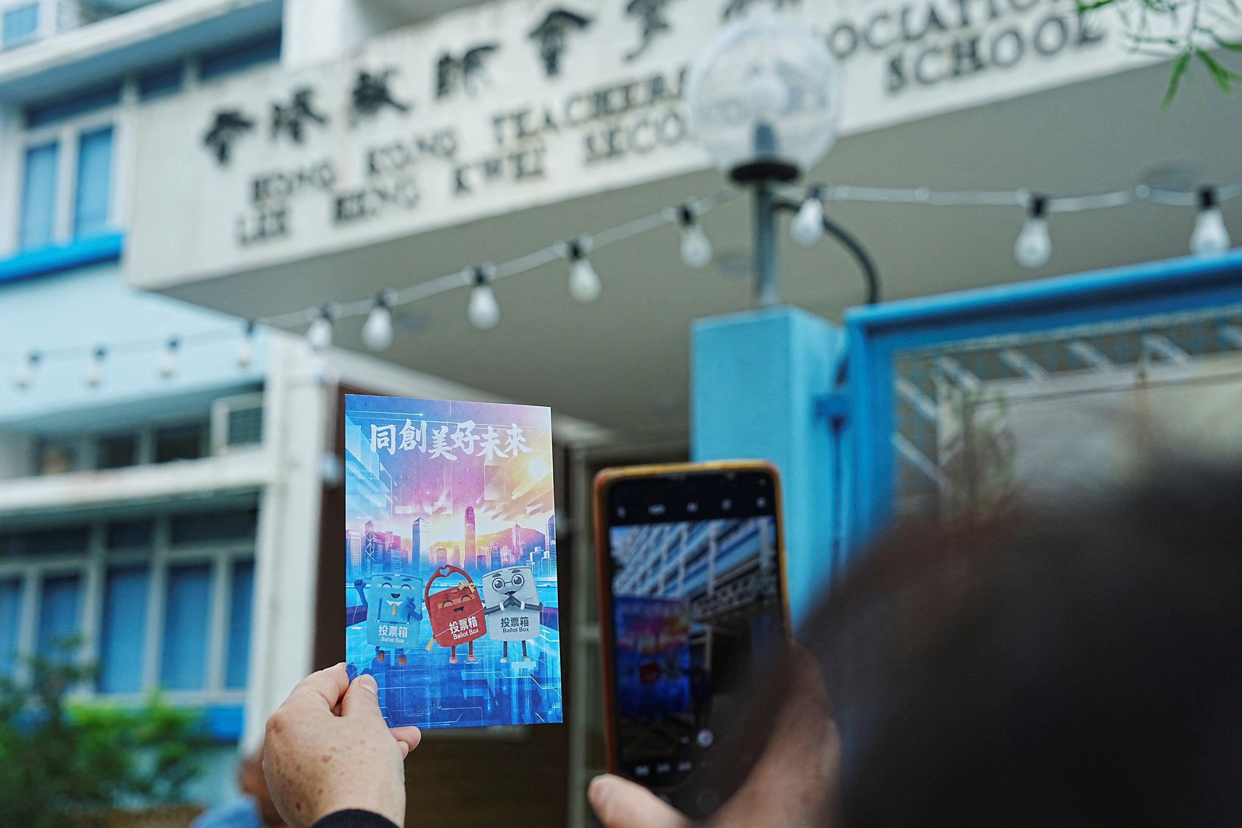有市民在票站外手持寫有「同創美好未來」的心意卡拍照。