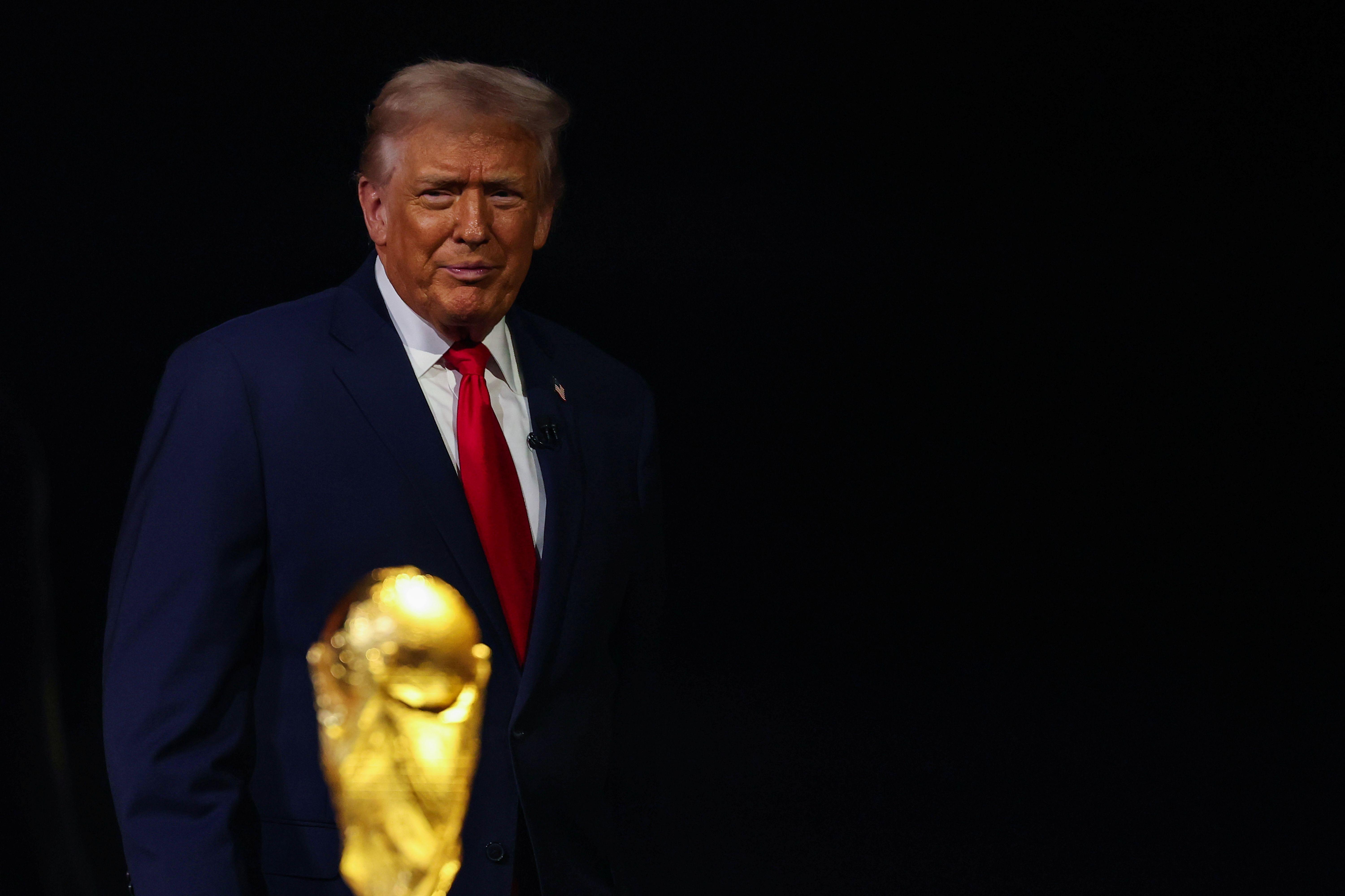 الرئيس الأمريكي دونالد ترامب يقف قرب كأس العالم، بينما حذرت "ذا ميرور" من أن سياسات الدخول إلى الولايات المتحدة قد تحول البطولة من حدث رياضي جامع إلى رمز للانقسام.