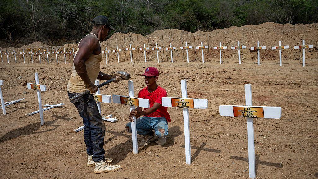 Una persona pone una cruz en el cementerio La Esperanza