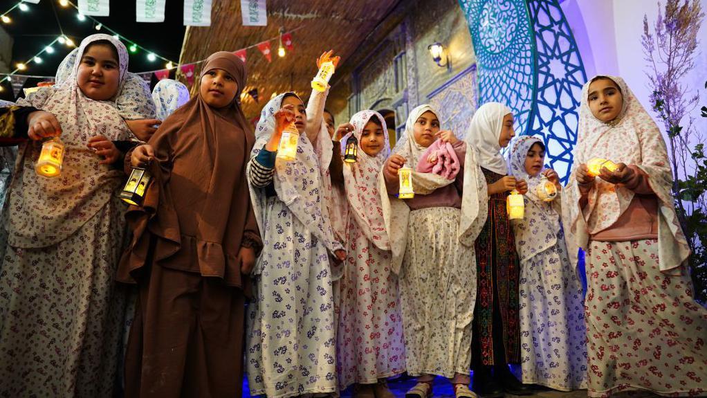 عدد من الأطفال "الفتيات" يحتفلنّ بقدوم شهر رمضان وهنّ يحملنّ الفوانيس في المدينة القديمة بالموصل، العراق، في 28 فبراير/ شباط 2025.