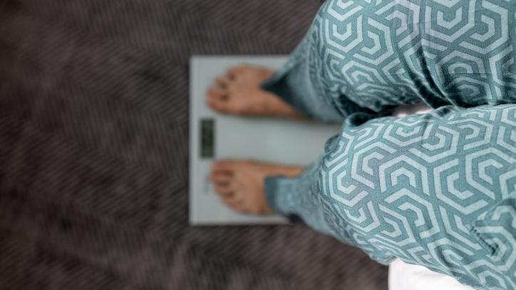 Pernas de uma pessoa que est&aacute; sobre uma balan&ccedil;a