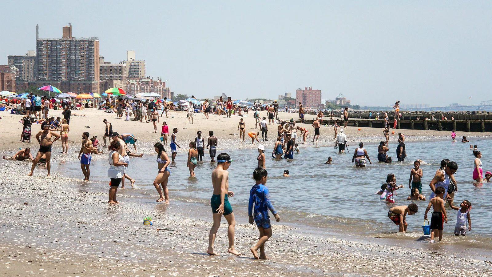 Playa con arena y piedras, y mucha gente