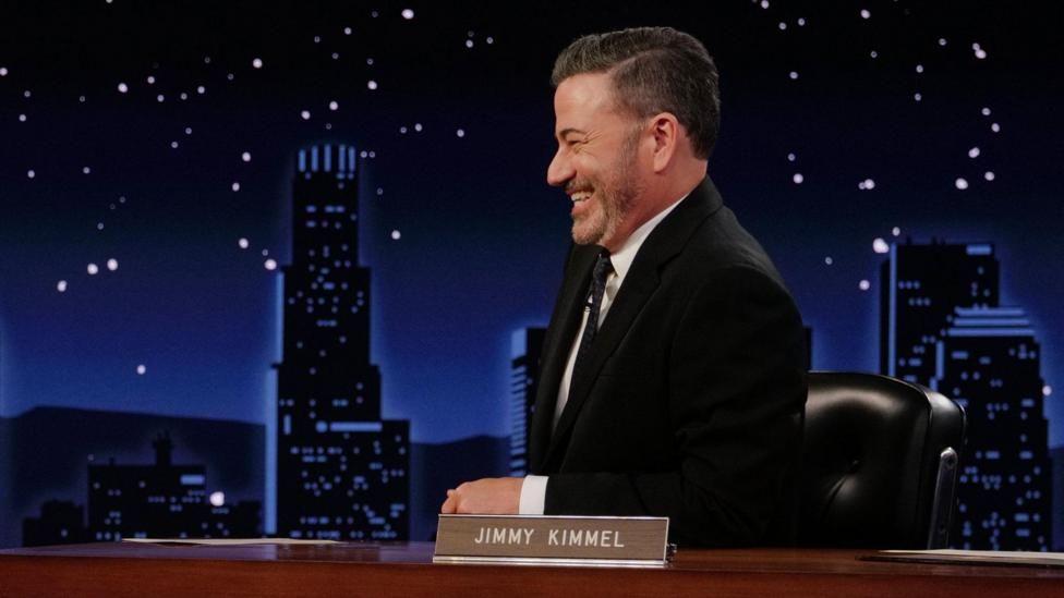 Jimmy Kimmel sonriente y de perfil en el escenario de su programa