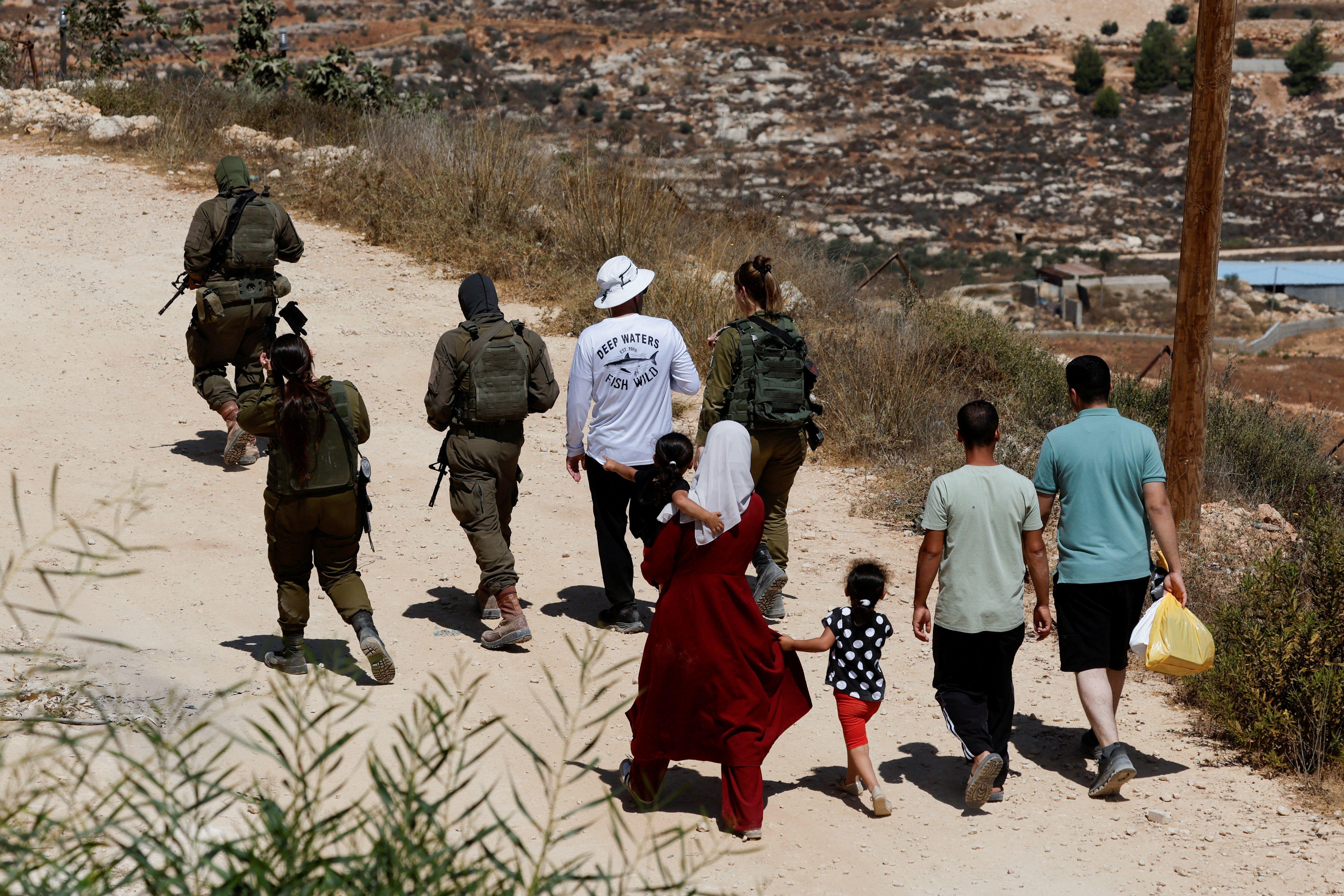 الفلسطيني الأمريكي لؤي أبو ريدة يسير برفقة أفراد من الجيش الإسرائيلي وجاريه رقية ويوسف حسن قرب منزله في قرية قصرة بالضفة الغربية المحتلة، بعد تمكنه من الوصول إليه، 19 أغسطس/آب 2026. وكان مستوطنون إسرائيليون قد طوقوا المنزل لأكثر من أسبوع.