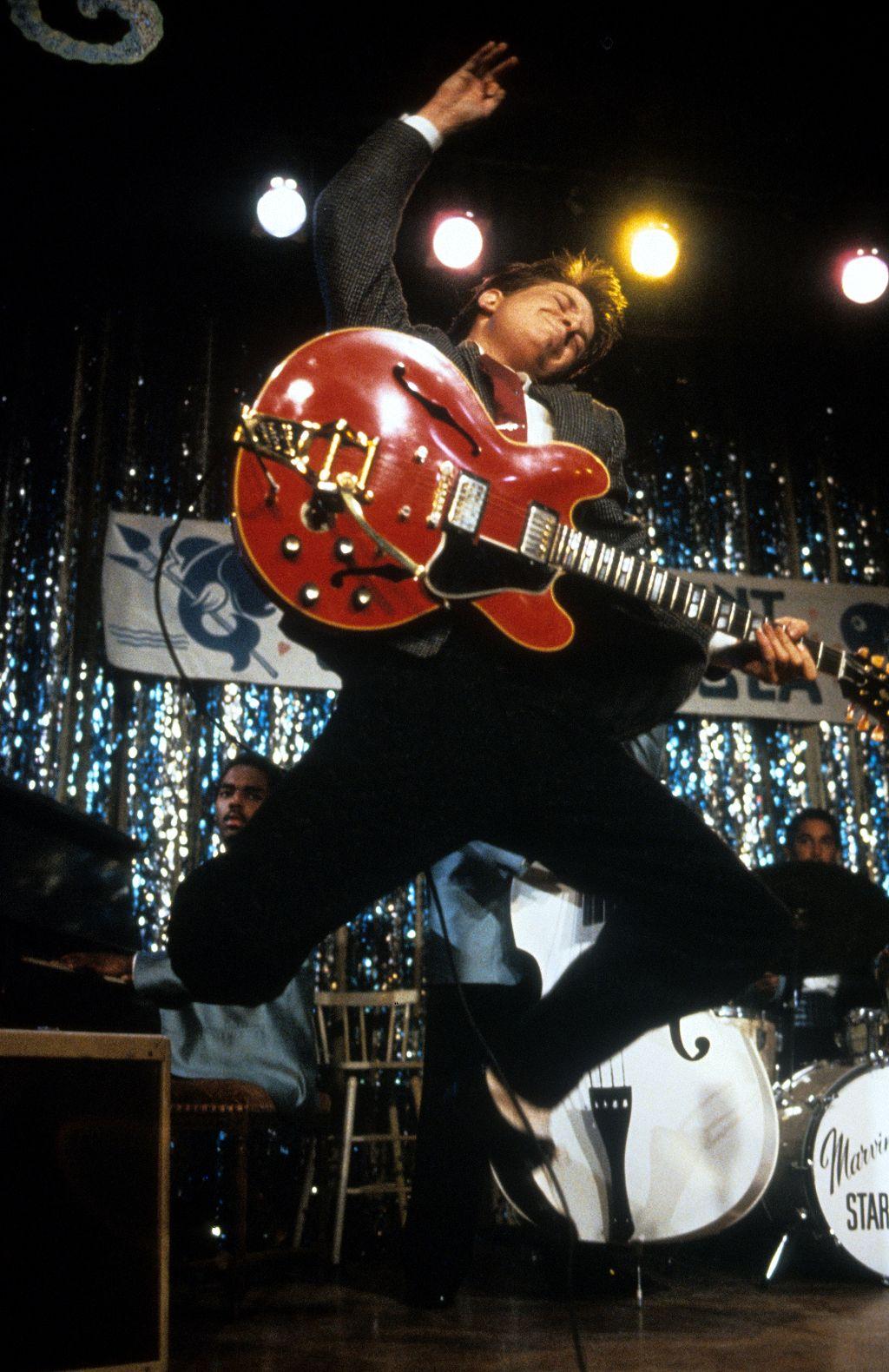 Michael J. Fox con guitarra eléctrica saltando en imagen de la película