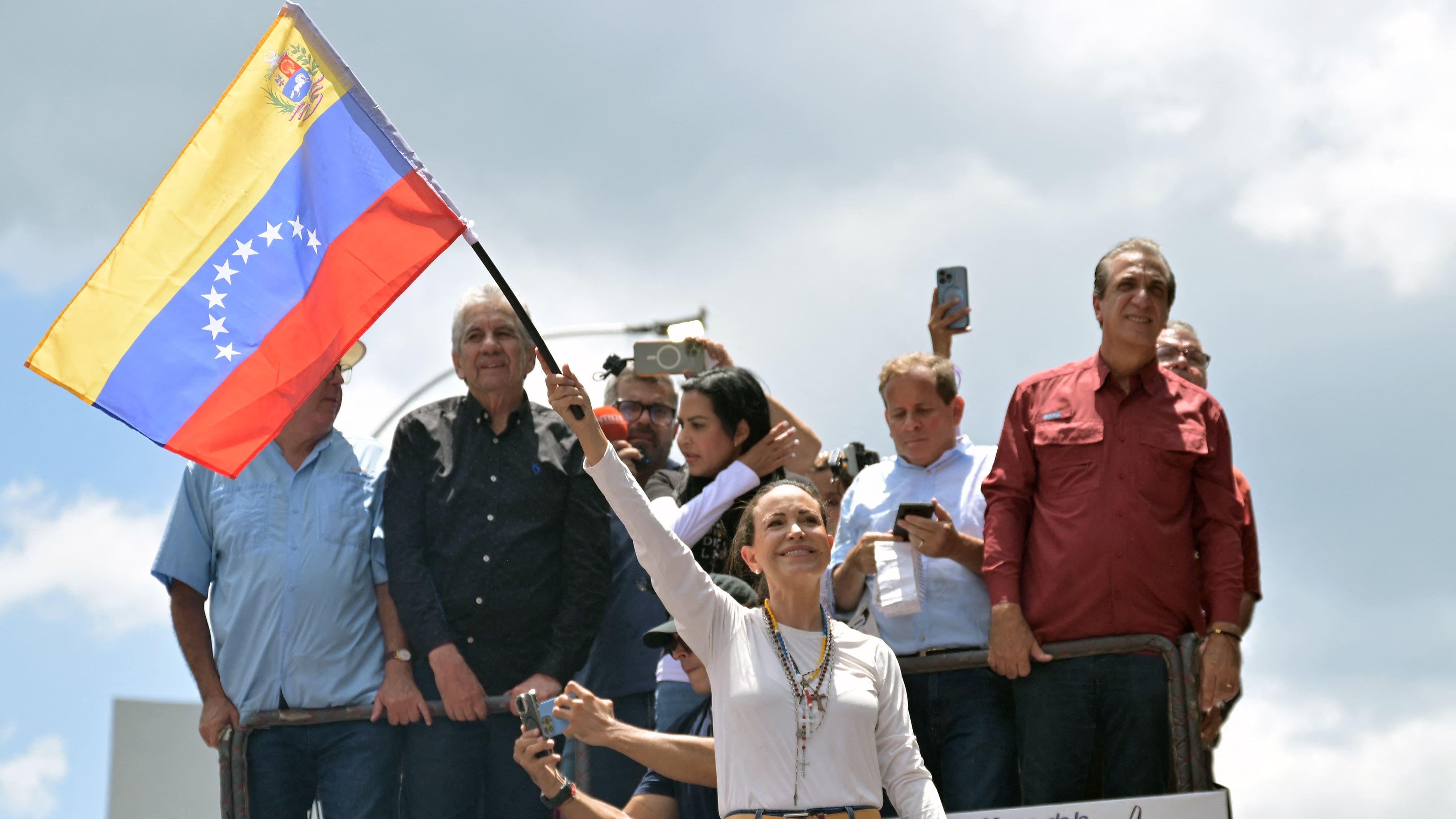 Machado ondea una bandera venezolana y sonríe.