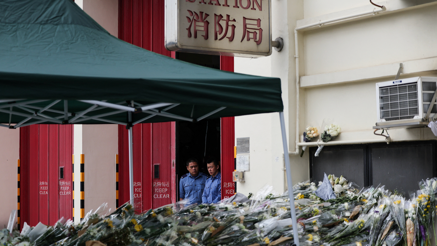 在沙田消防局入口處，消防員們正在哀悼，人們繼續獻花悼念在太埔宏福苑火災中殉職的消防員何偉豪。