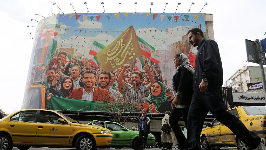 La gente camina por las calles de la capital iraní, Teherán, mientras la vida cotidiana continúa.