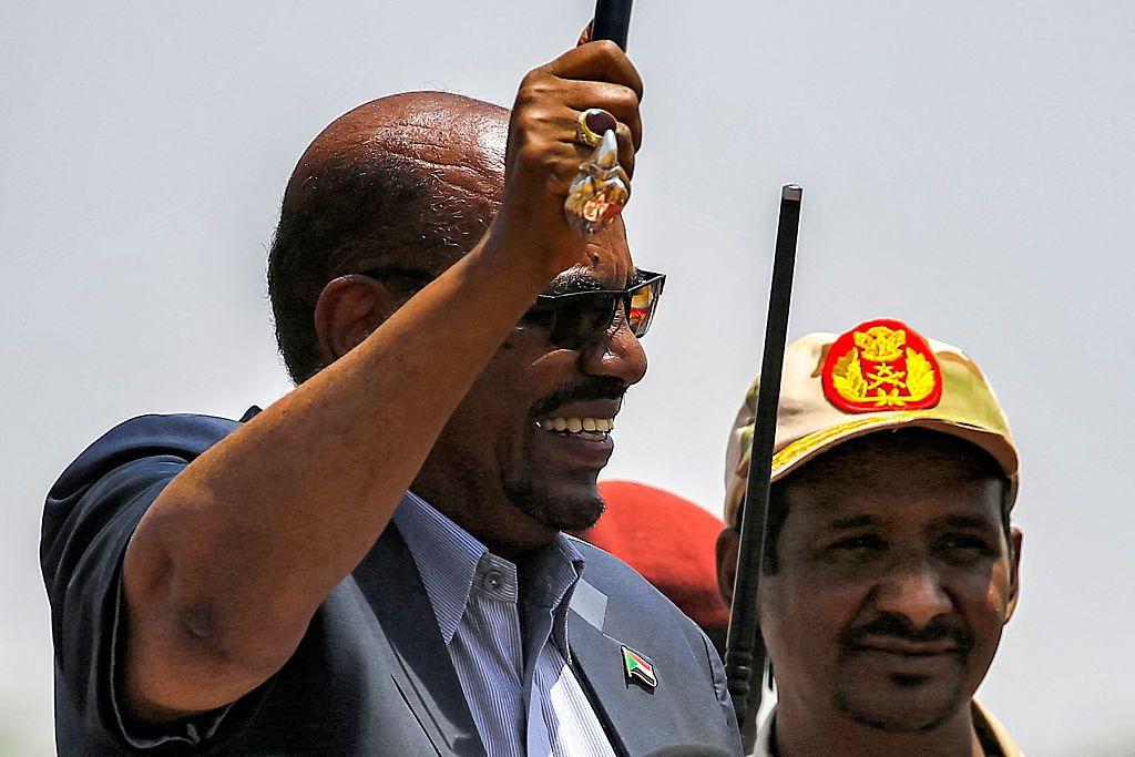  Omar al-Bashir (L) waves a walking stick as he gives a speech at the headquarters of the Rapid Support Forces (RSF) paramilitaries in Umm al-Qura in South Darfur State, while RSF commander Mohamed Hamdan Daglo, wearing a cap, looks on