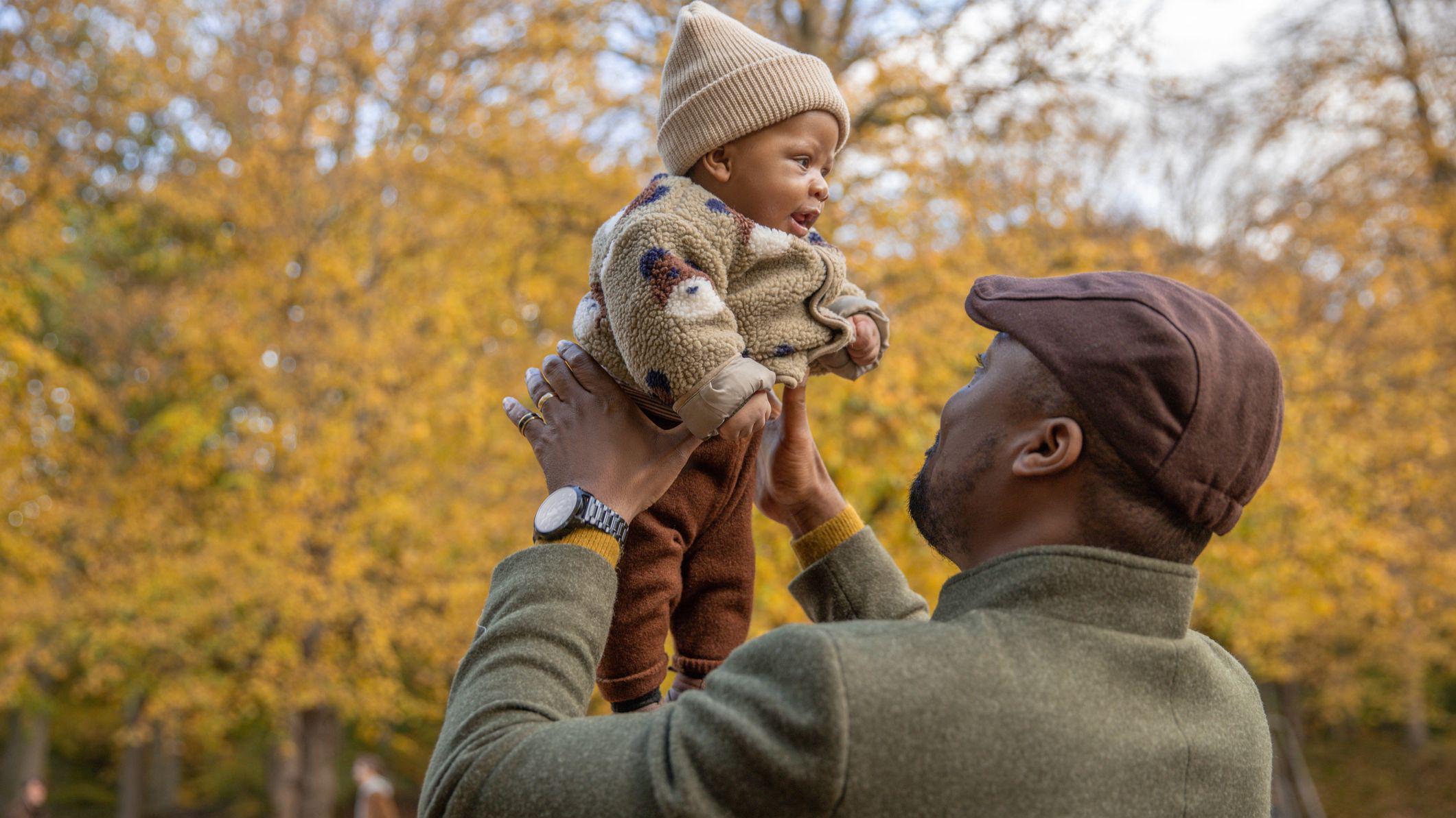 رجل يحمل طفلا ويلاعبه في حديقة