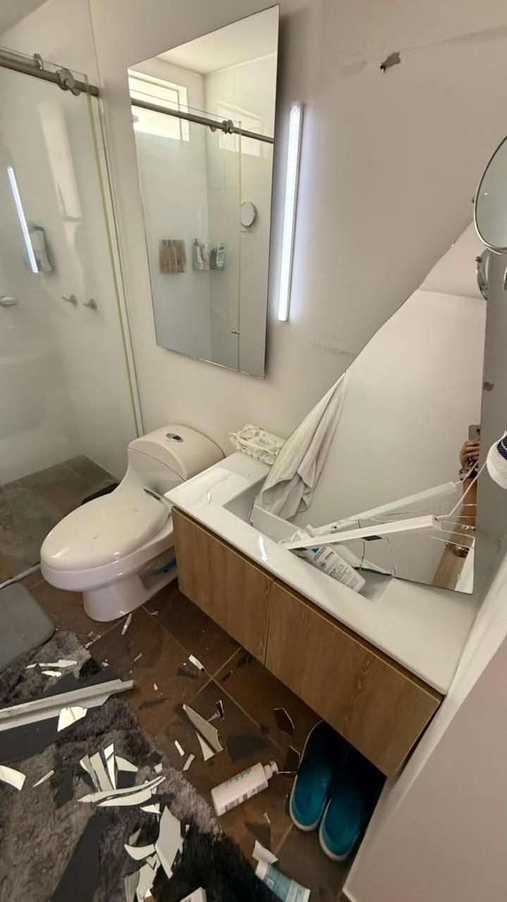 El baño del apartamento de Molina con un espejo roto y varias cosas y restos en en el piso