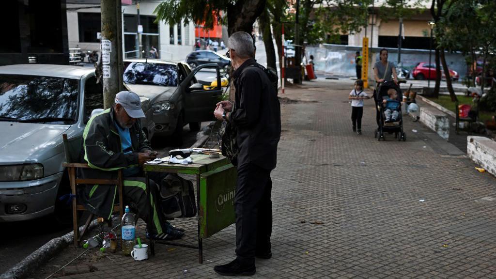 Un hombre cuenta billetes de guaraníes en una calle de Asunción