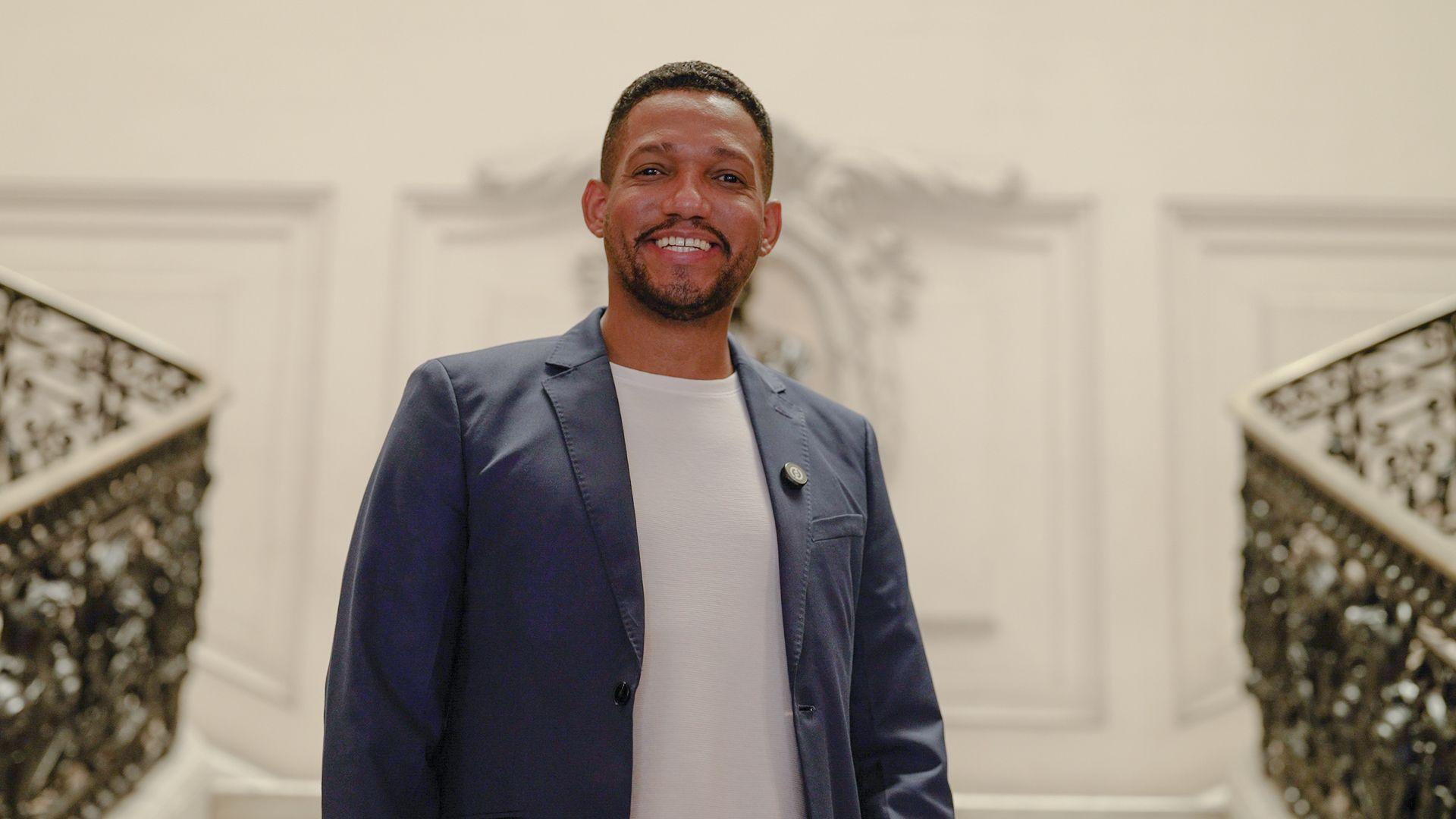 Rick Azevedo sorrindo e olhando para a c&acirc;mera em uma escadaria imponente na C&acirc;mara dos Vereadores do Rio de Janeiro