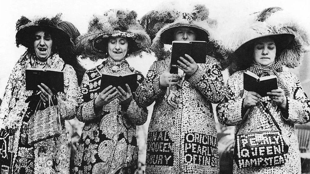 Četiri žene obučene u raskošnim kostimima sa šeširima od perja