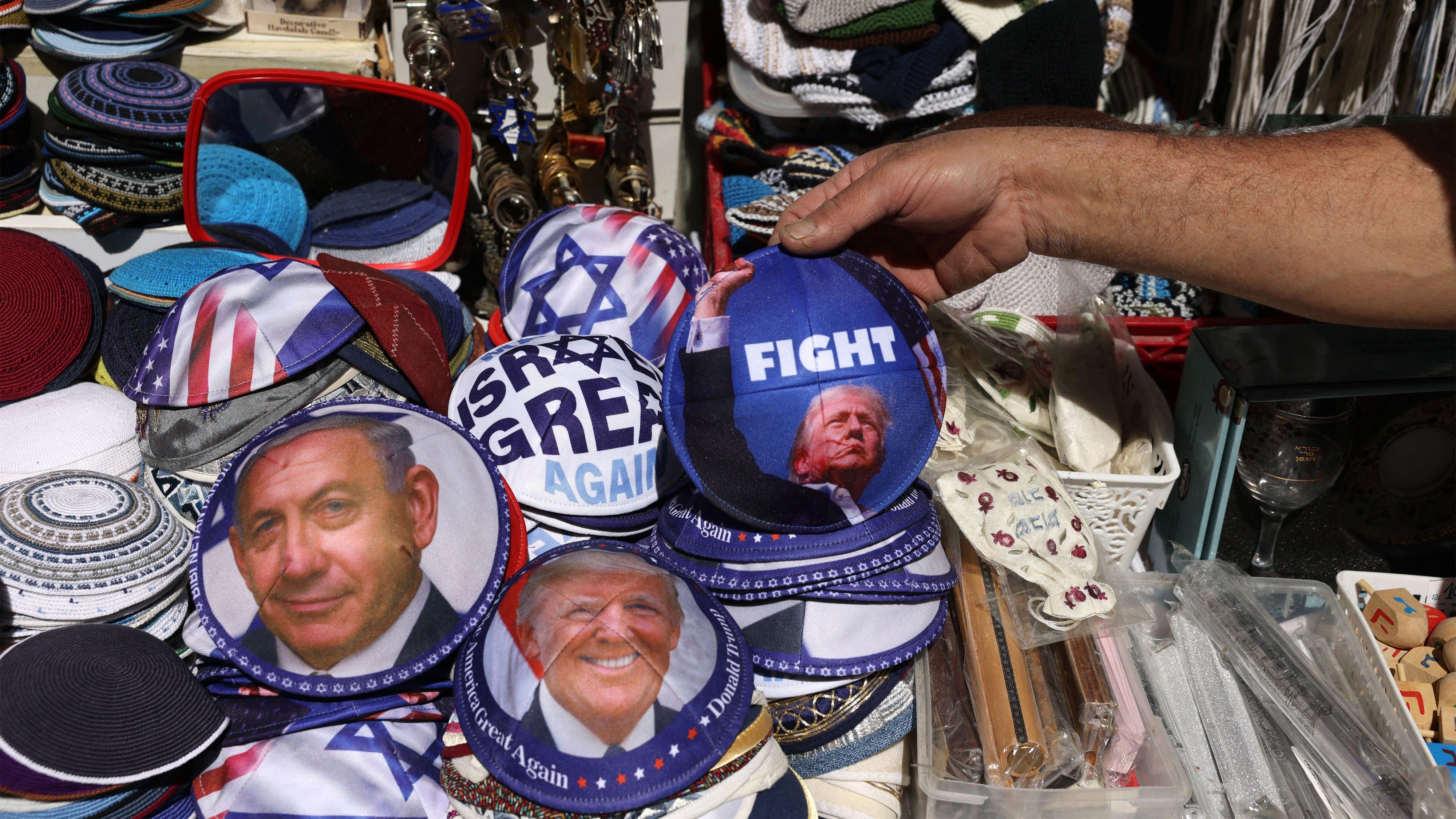 يعرض بائع إسرائيلي قبعات يهودية تُعرف باسم "كيباه" (اليرمولكا)، تحمل صورة الرئيس الأمريكي دونالد ترامب (يمين) ورئيس الوزراء الإسرائيلي بنيامين نتنياهو، في متجره بشارع يافا، غرب القدس، في 12 مارس/آذار 2026. 