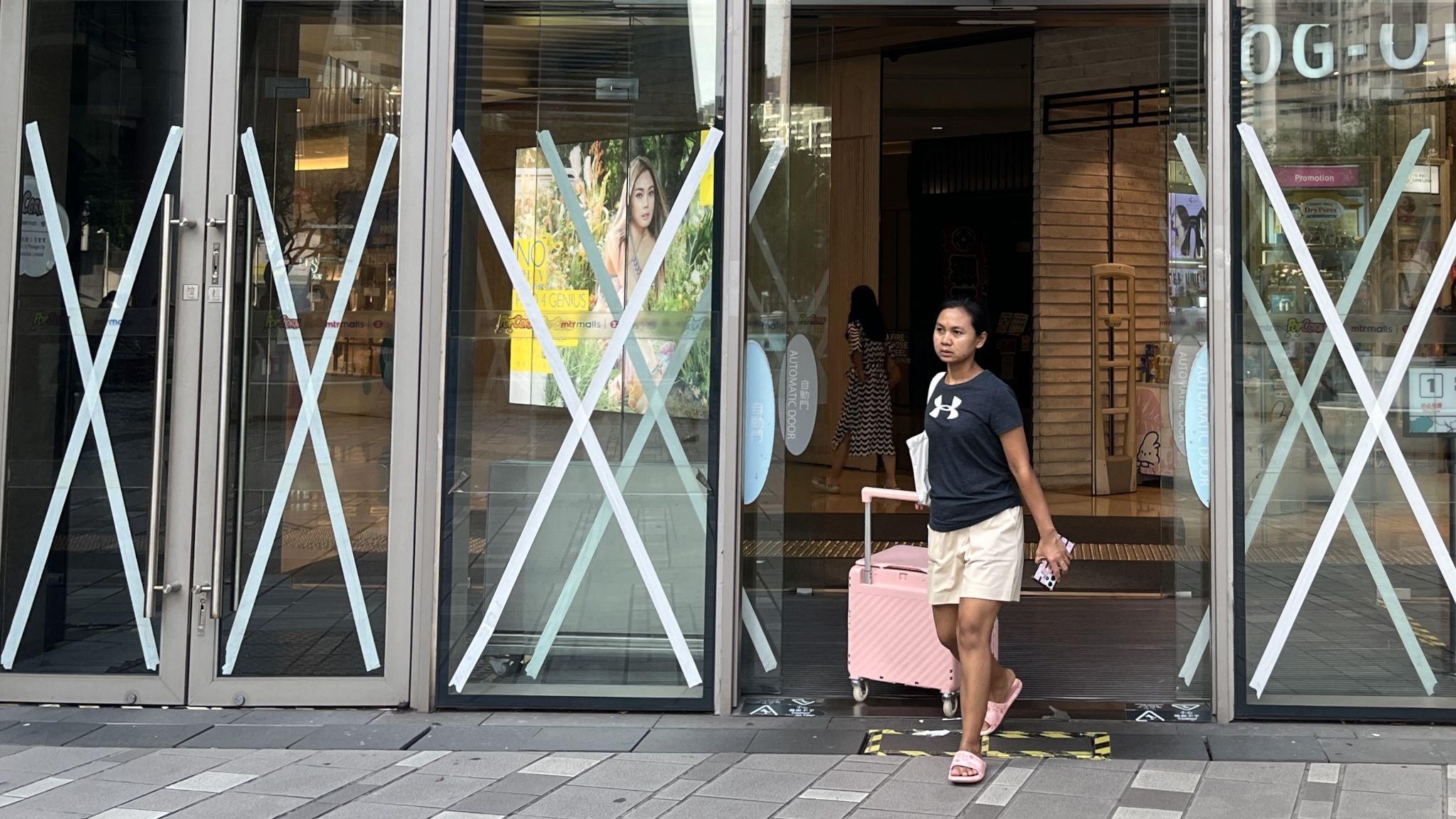 香港將軍澳某購物商場一位女士（右）走出貼滿皺紋膠卷的玻璃大門（BBC中文圖片22/9/2025）