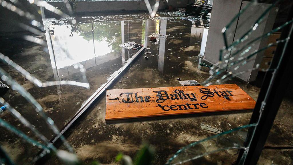 Attackers vandalised and torched The Daily Star office, causing extensive damage. A shattered sign lies amid broken glass at reception.