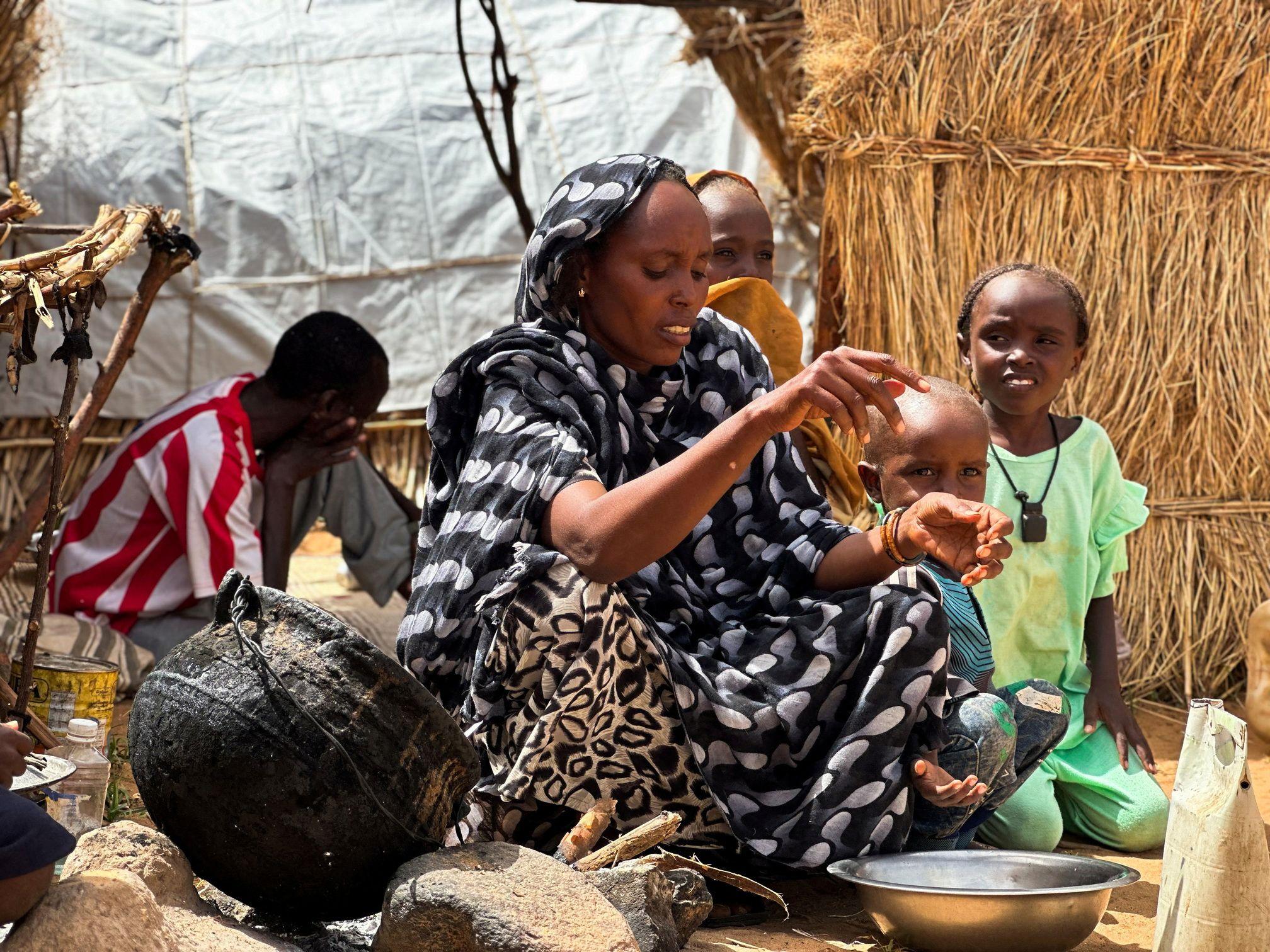 صورة لنازحة سودانية تُعد الطعام لأطفالها داخل مخيم للنازحين في دارفور غربي السودان