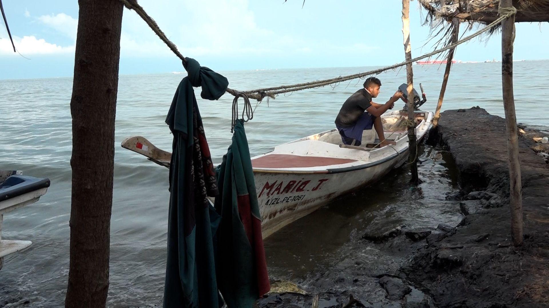 Un joven en una lancha blanca amarrada en un muelle.
