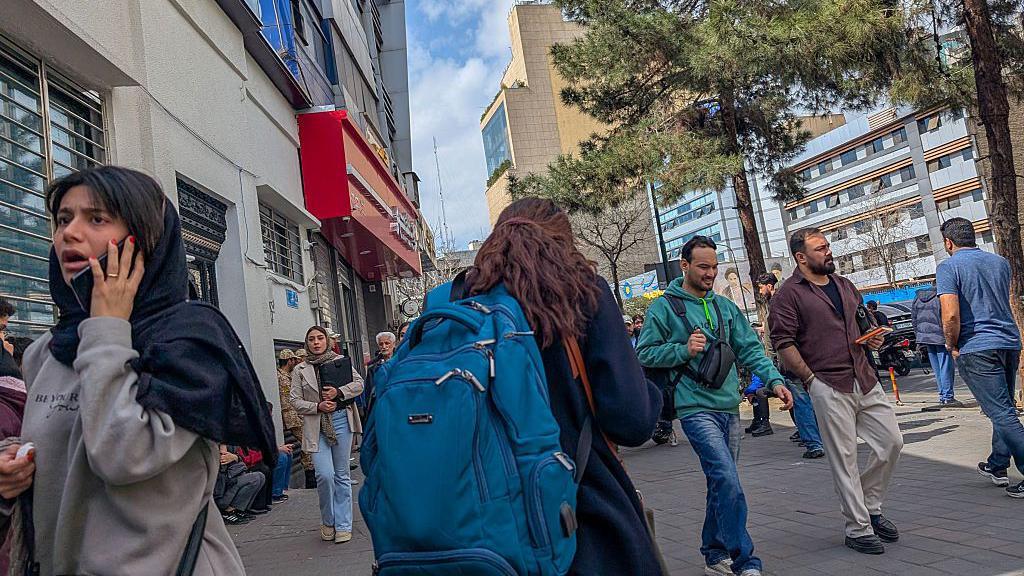 Varias personas llaman por teléfono en las calles de Teherán