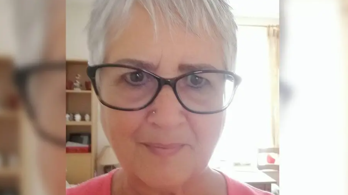 Photograph selfie of Judith Rhead. She has silver short hair- and wears black wide rimmed glasses. She has brown eyes and looks into the camera. 