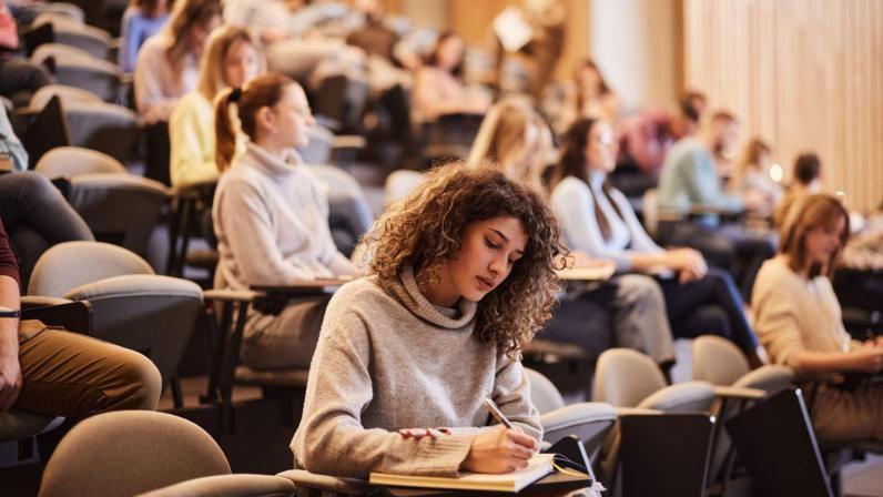 Joven tomando notas en una clase en la universidad. 