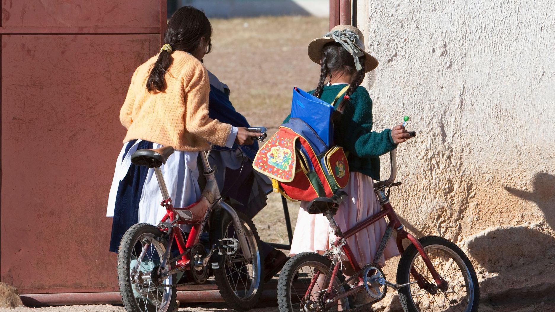 Dos niñas de espaldas en bicicletas en Oruro, Bolivia.