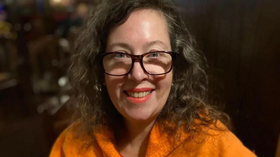 Mujer sonriendo vestida con una sudadera naranja