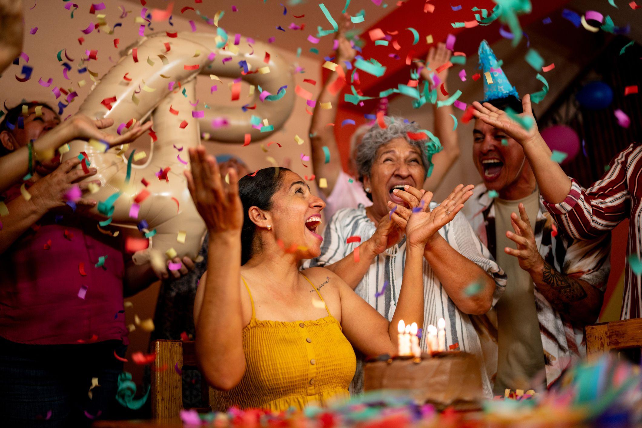 Una familia latina le celebra el cumpleaños a una mujer, y todos están cantando una canción de cumpleaños alrededor de un pastel