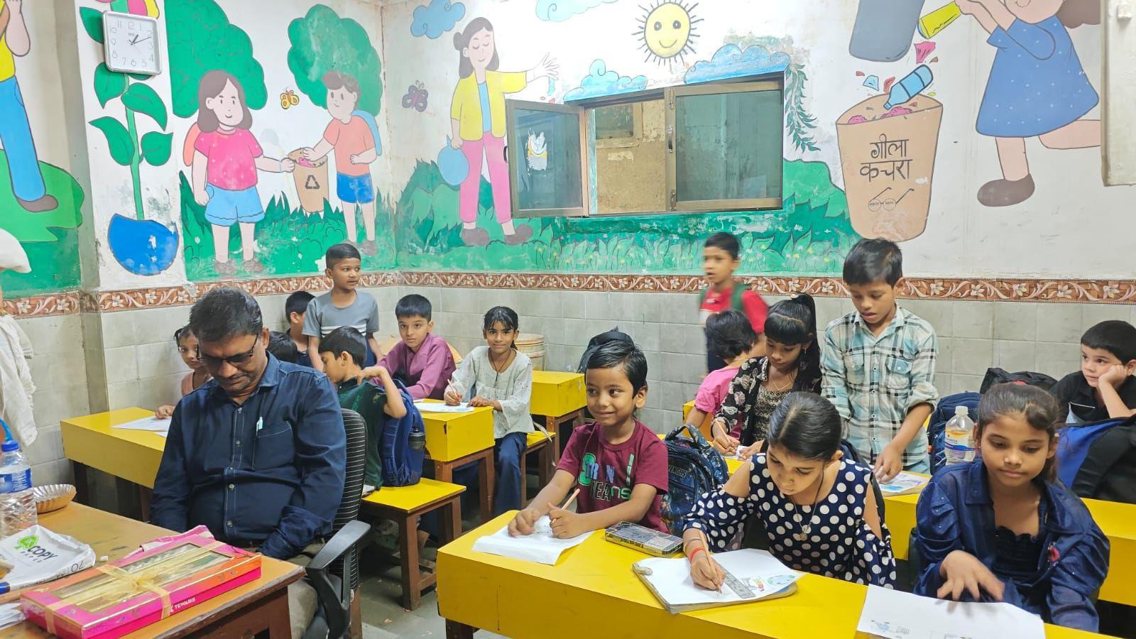 Los niños se sientan en un aula con paredes cubiertas de murales sobre la eliminación de residuos.
