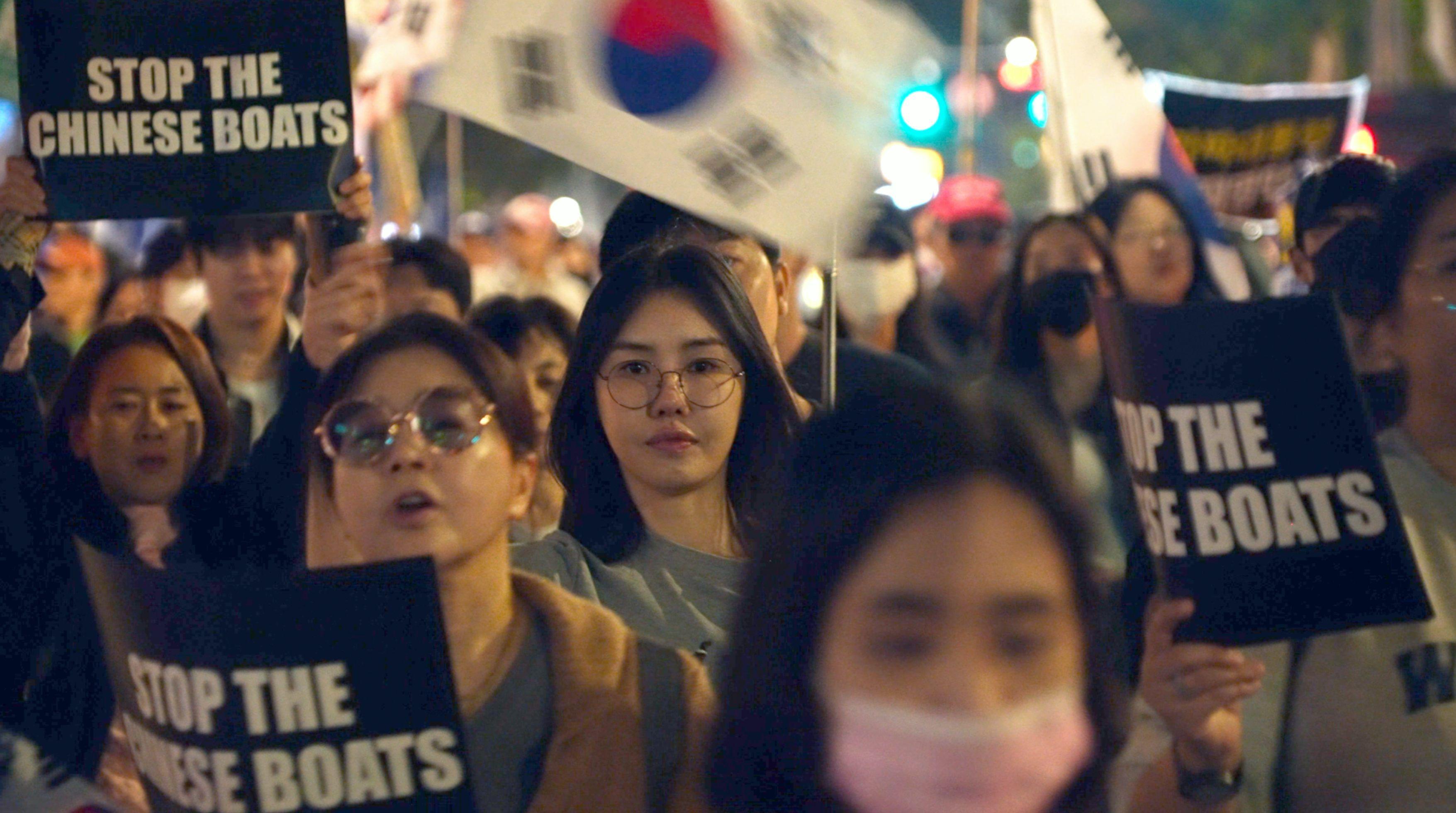 韓國首爾梨泰院一場由「自由大學」組織的反華集會上,一群女示威者舉起「制止中國船隻」標語牌(BBC韓語圖片18/10/2025)