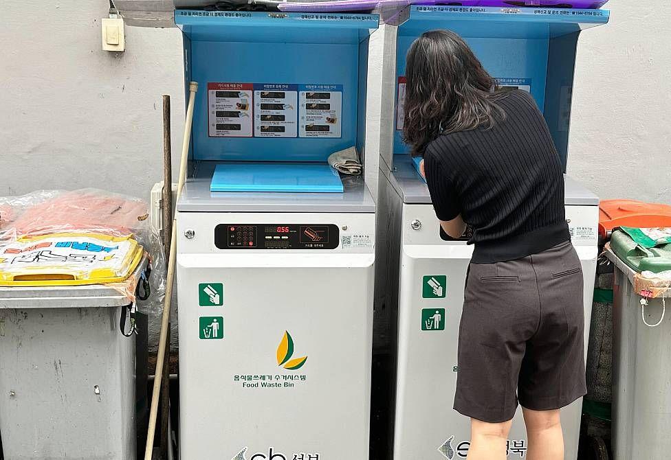 Mulher de costas colocando resíduos em uma máquina branca